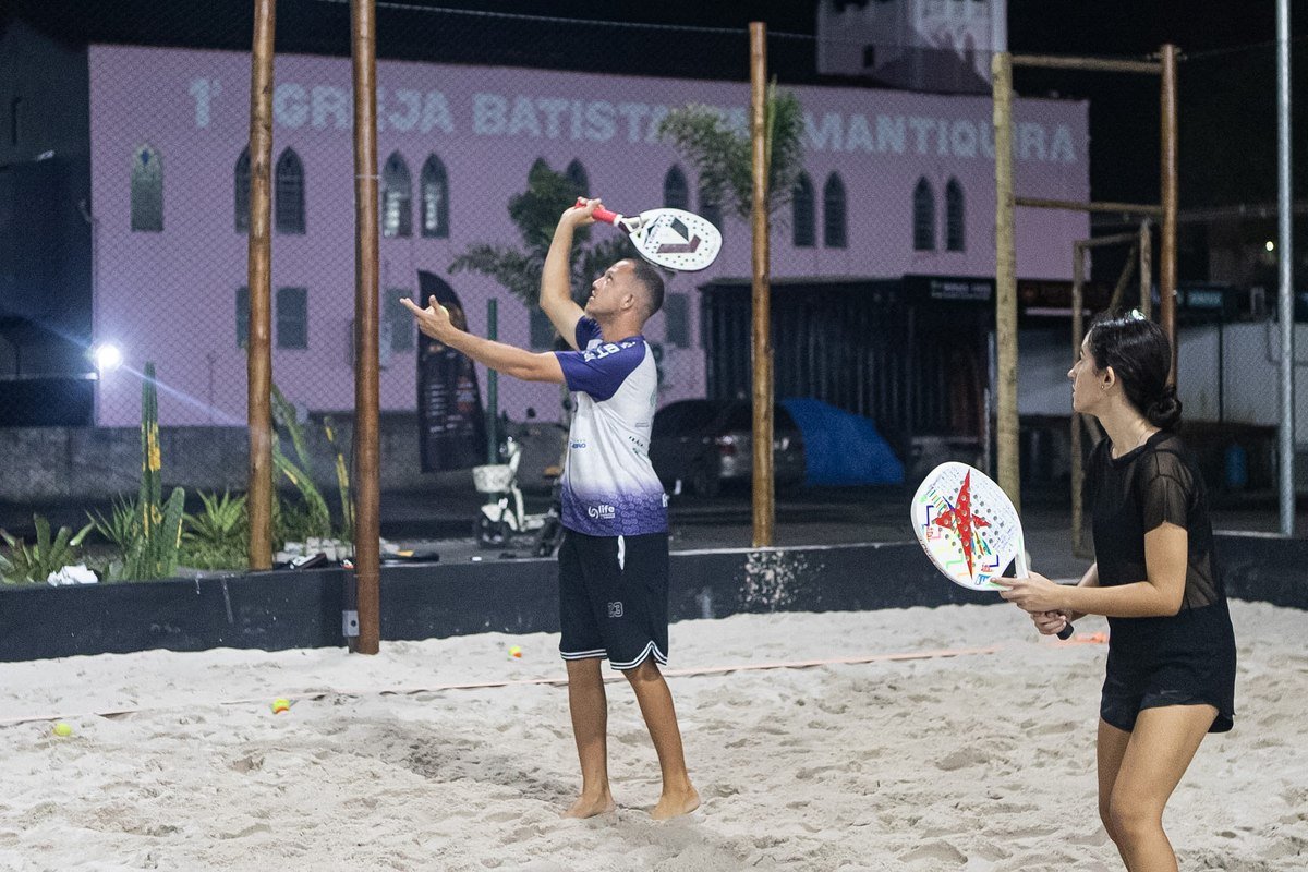 Aluno saltando para o smash em aula de beach tennis