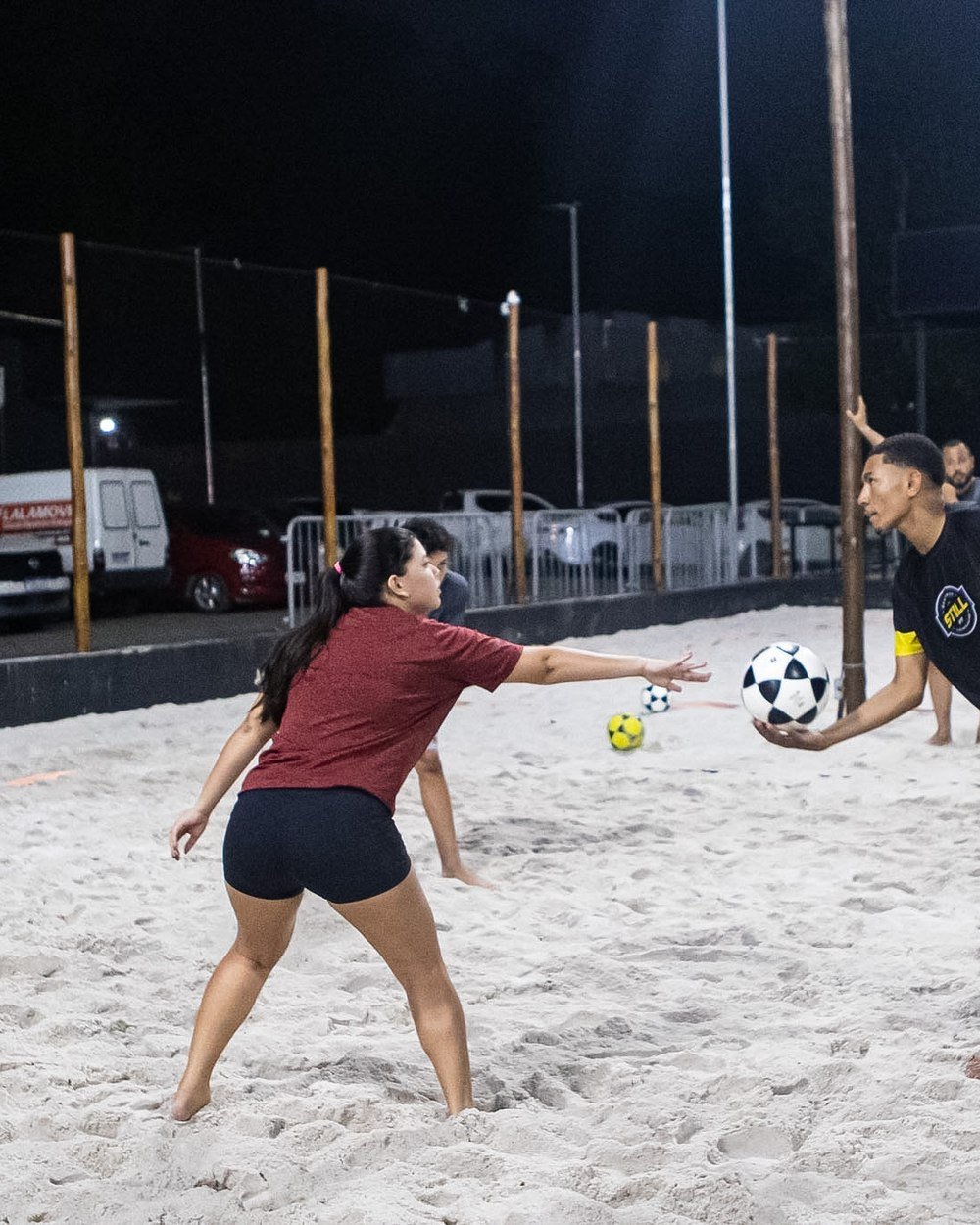 Professor orientando uma aluna iniciante na quadra de areia